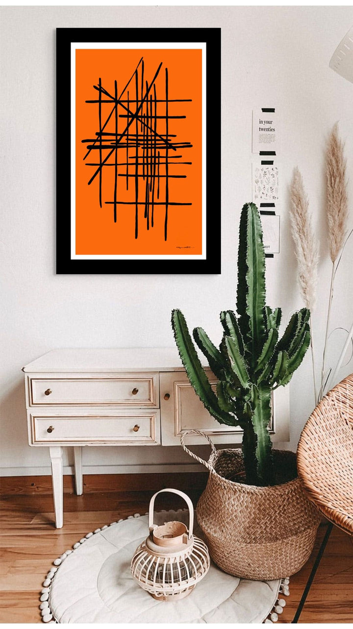 Room interior with a cactus plant, framed abstract art in orange, and a white cabinet.