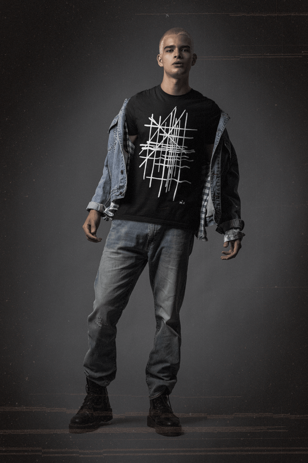 Man wearing a black t-shirt with white abstract graphic design and blue jeans on a dark background