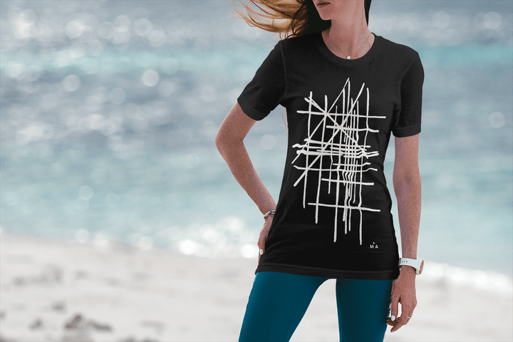Woman wearing a black t-shirt with white geometric design on a beach