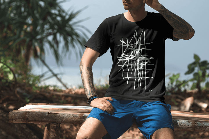 Man wearing a black t-shirt with a white abstract graphic design, sitting outdoors.