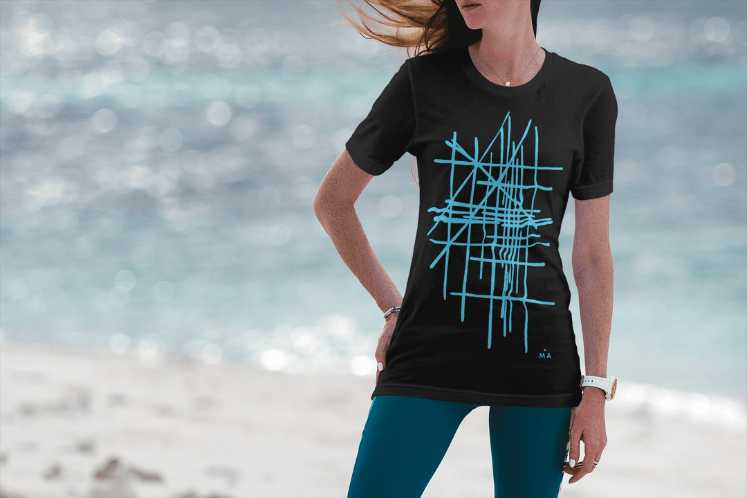 Woman wearing a black abstract t-shirt with blue geometric design on a beach