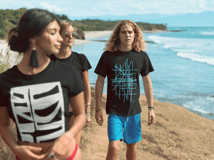 Three friends  standing on a beach with ocean view, wearing black abstract t-shirts with unique designs.