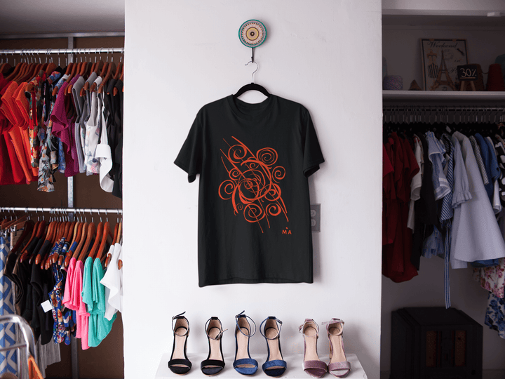 The Trend - Abstract T-Shirt by Miamiabstract.com, featuring a bold orange swirl design, hangs on a white wall between two clothing racks. Below, five vibrant high-heeled shoes are neatly lined up.