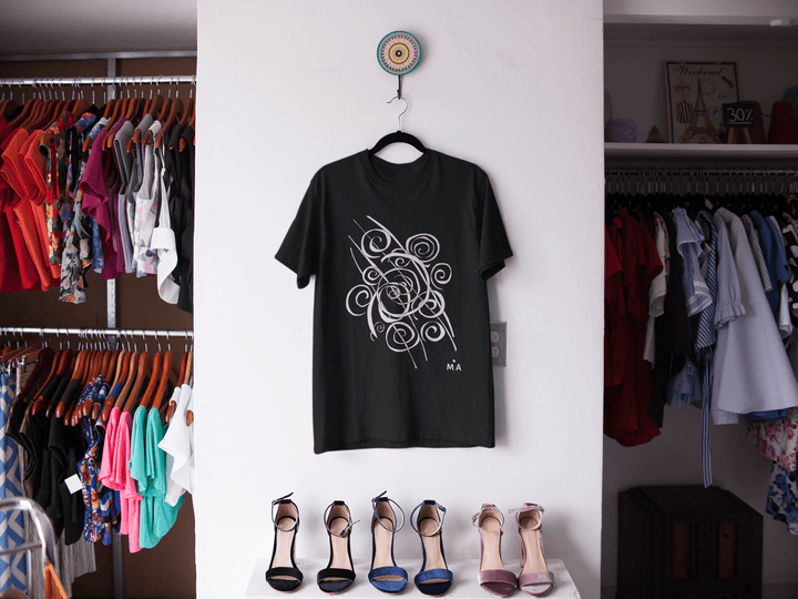 The Trend - Abstract T-Shirt by Miamiabstract.com, featuring a bold black and white swirl design, hangs on the wall between two racks. Below it, five colorful pairs of high-heeled shoes are neatly lined up.