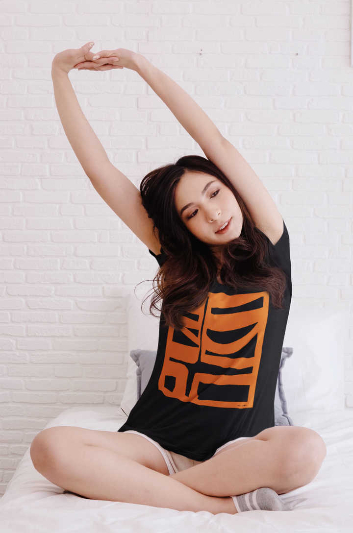 woman stretching on a bed wearing abstract t shirt BI 500 in orange